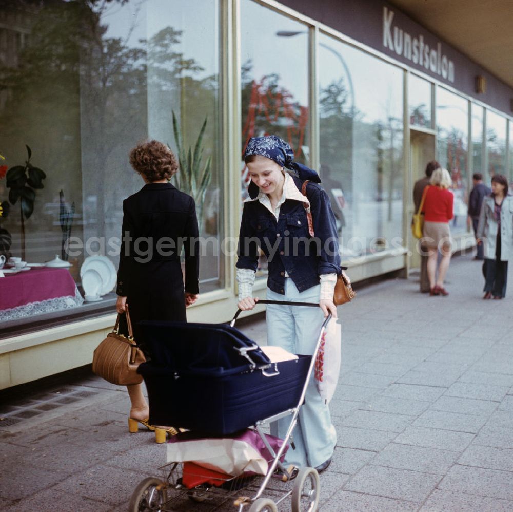 GDR photo archive: Berlin - Eine junge Mutter genießt den Spaziergang mit ihrem Baby im Kinderwagen Unter den Linden in Berlin. Im Hintergrund der Berliner Kunstsalon.