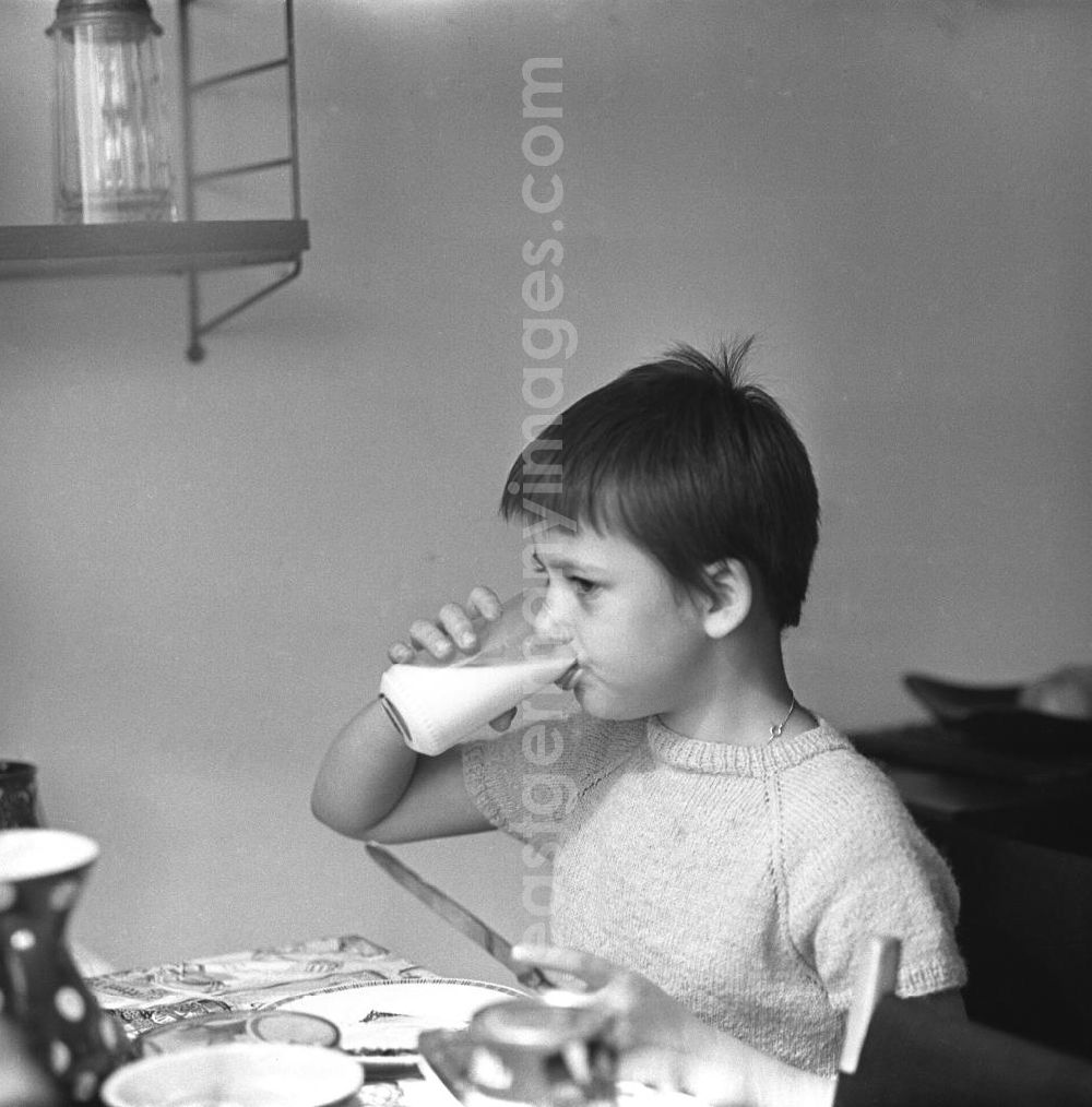 GDR picture archive: Berlin - Zwei Tage im Leben einer alleinerziehenden Frau mit zwei Kindern in Ostberlin. Zwischen Privatem, Arbeit und Weiterbildung ( EDV Kurs ). Die Familie sitzt am Tisch und ißt Abendbrot, ein Mädchen trinkt Milch aus einem Glas.