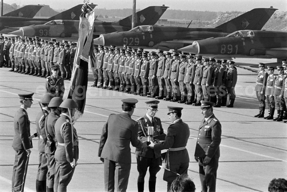 GDR image archive: Jänschwalde - Media-effective passage of the honorary formation of the flag command of troops from the fighter squadron Wilhelm Pieck of the air force at the pre-launch line of the stationed MiG-21 PFM weapon system as part of a disarmament action at the Drewitz airfield of the National People's Army NVA office in Jaenschwalde in the state of Brandenburg on the territory of the former GDR, German Democratic Republic