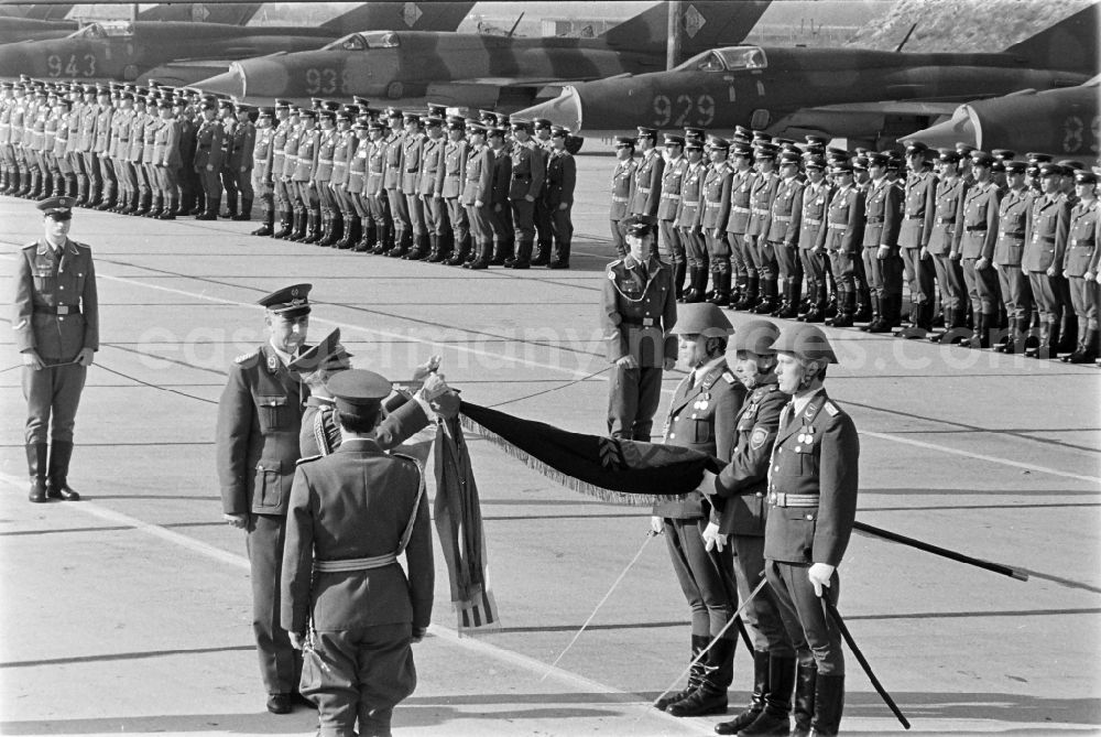 GDR picture archive: Jänschwalde - Media-effective passage of the honorary formation of the flag command of troops from the fighter squadron Wilhelm Pieck of the air force at the pre-launch line of the stationed MiG-21 PFM weapon system as part of a disarmament action at the Drewitz airfield of the National People's Army NVA office in Jaenschwalde in the state of Brandenburg on the territory of the former GDR, German Democratic Republic