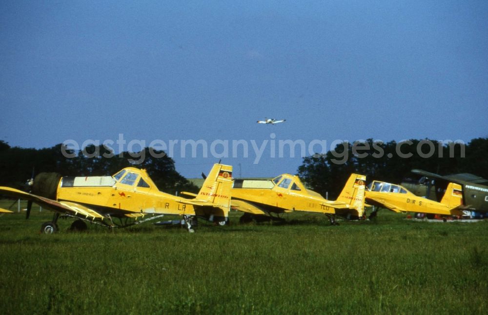 GDR picture archive: Kyritz - Agricultural aircraft INTERFLUG type M-18 on a meadow in Kyritz in today's state of Brandenburg. The agricultural aircraft from liquid and solid manure deploy and is also used for fire fighting. Best quality according to original artwork!
