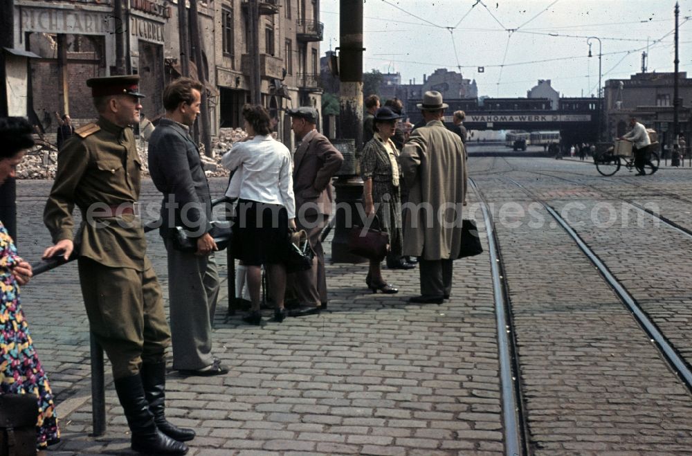 GDR photo archive: Halle (Saale) - Passengers and a Soviet soldier waiting at the tram-stop Riebeckplatz. Debris in the background in Halle (Saale) in the state Saxony-Anhalt on the territory of the former GDR, German Democratic Republic