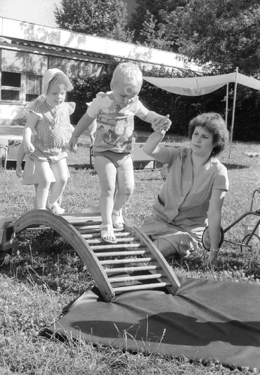 Berlin: Children play together with her educator in the garden and do gymnastics about a wooden rung curve in Berlin, the former capital of the GDR, German democratic republic