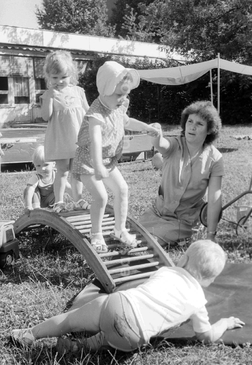 GDR image archive: Berlin - Children play together with her educator in the garden and do gymnastics about a wooden rung curve in Berlin, the former capital of the GDR, German democratic republic