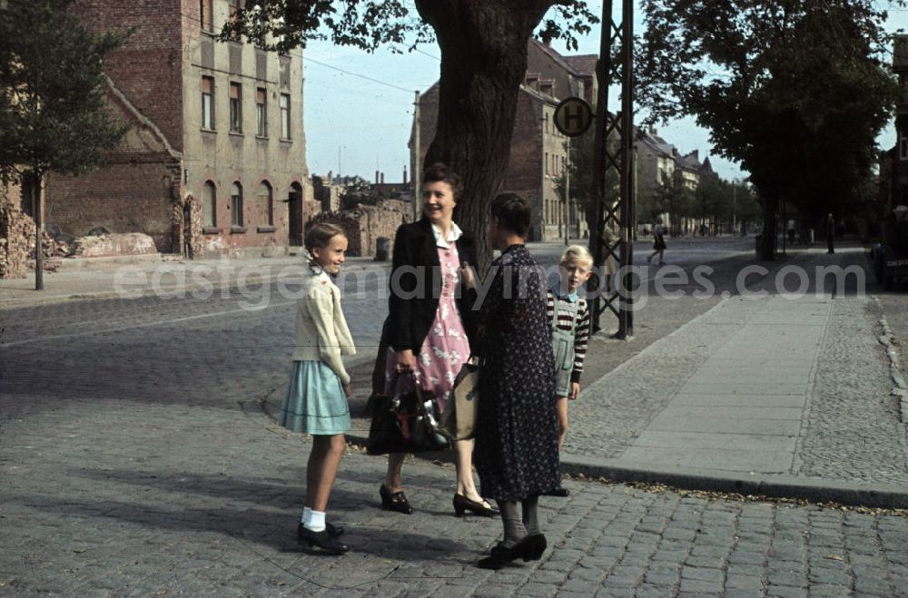 Merseburg: Frauen und Kinder auf der Straße im Gespräch. Trümmer im Hintergrund. Women and children in a conversation on the street. Debris in the background.