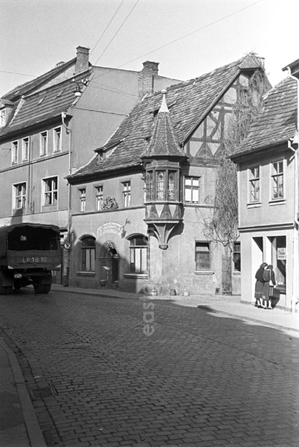 Weimar: Alltagsszene in Weimar. LKW fährt auf Straße (Kopfsteinpflaster) vorbei an Wohnhäuser / Altbauten. Zwei Frauen stehen vor einen Schaufenster.