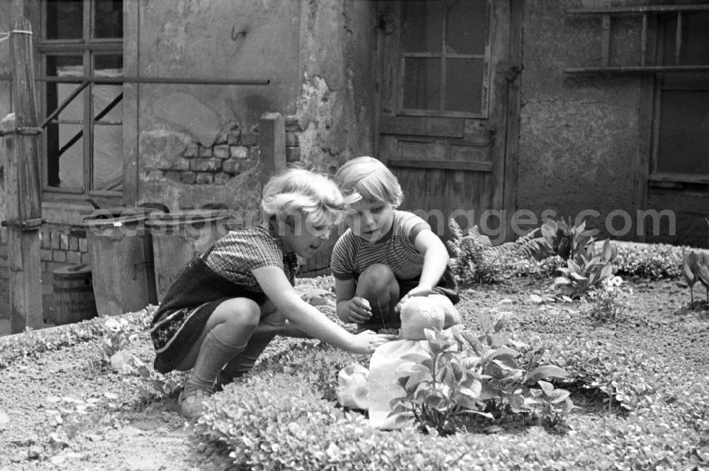 GDR picture archive: Weimar - Zwei Mädchen spielen mit ihrer Puppe auf dem grün bepflanzten Hinterhof eines Altbaus in Weimar. [Bestmögliche Bildqualität nach Vorlage]