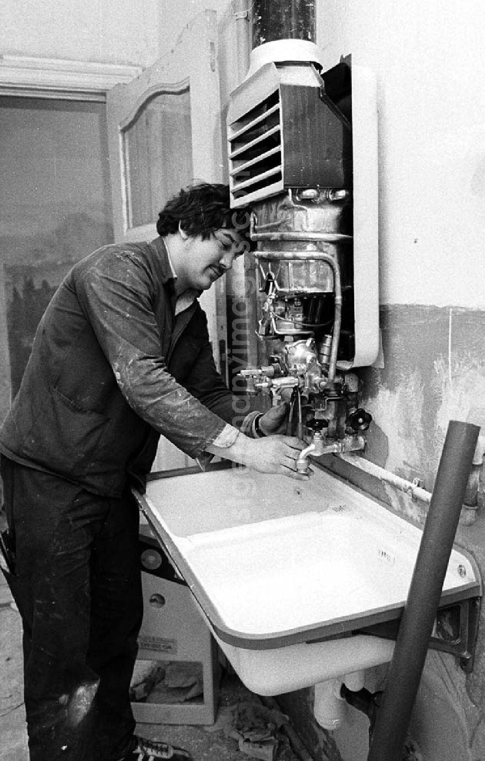 GDR picture archive: Berlin - Ein Arbeiter setzt in einem Altbau-Wohnhaus in der Britzer Straße in Niederschöneweide einen Boiler instand.
