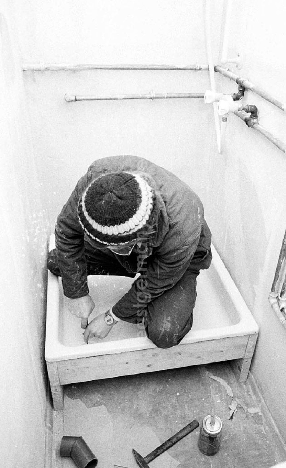 GDR image archive: Berlin - Ein Arbeiter setzt in einem Altbau-Wohnhaus in der Britzer Straße in Niederschöneweide eine neue Duschtasse in ein Badezimmer.