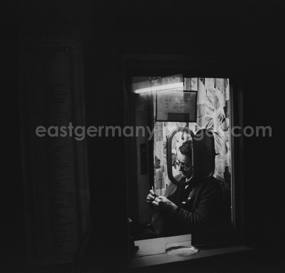 Berlin - Lichtenberg: An elderly woman sitting in a funicular ticket office and embroiders in Berlin - Lichtenberg