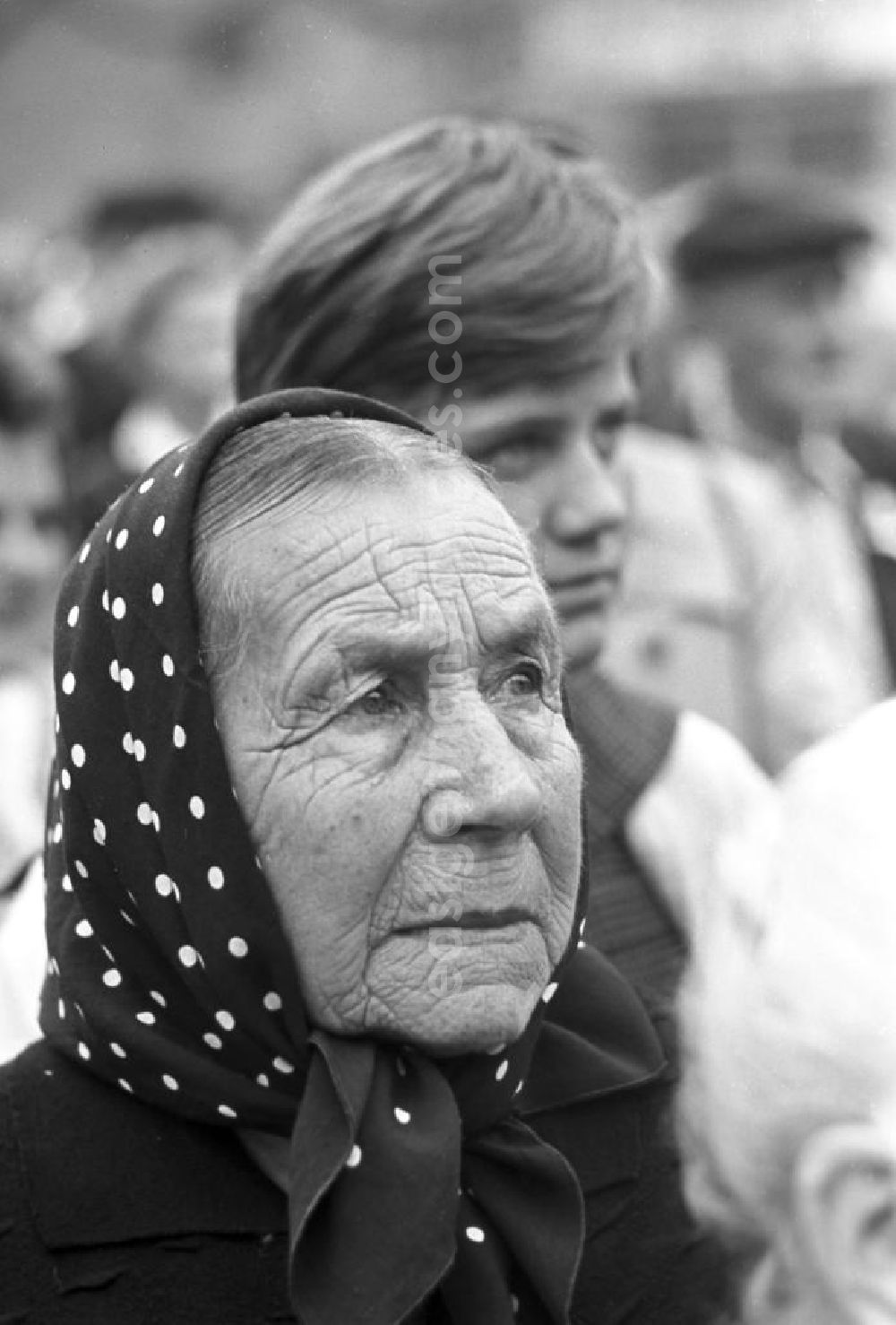 GDR picture archive: Freyburg - Porträtaufnahme einer alten Frau, die zum Winzerfest in Freyburg an der Unstrut der Musik der Blaskapelle der Sowjetarmee zuhört.