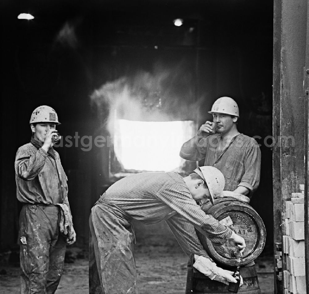 GDR image archive: Eisenhüttenstadt - Arbeiter vor einem Ofen im Eisenhüttenkombinat Ost (EKO) zapfen aus einem Fass Getränke.