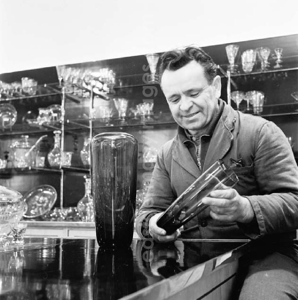 GDR photo archive: Weißwasser - Arbeiter vom Oberlausitzer Glaswerke hält Glas in Hand und schaut sich das Glas an. Verschieden Gläser stehen im Hintergrund im Regal.