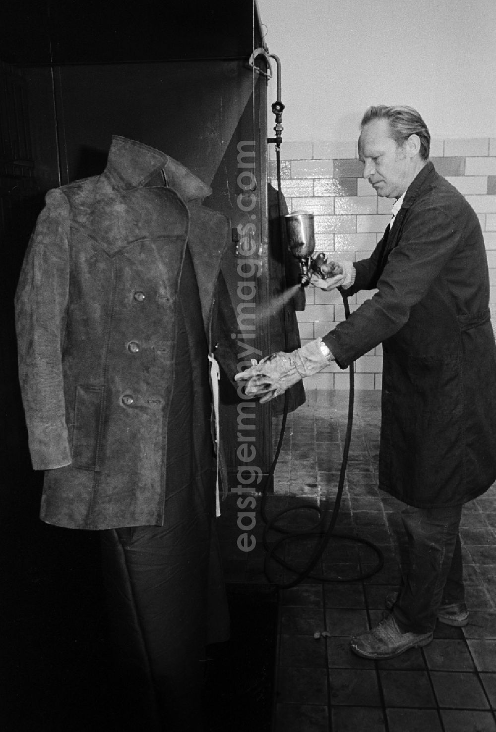 GDR image archive: Berlin - A worker in the VEB united laundrys Berlin Rewatex with clean of a coat in Berlin, the former capital of the GDR, German democratic republic