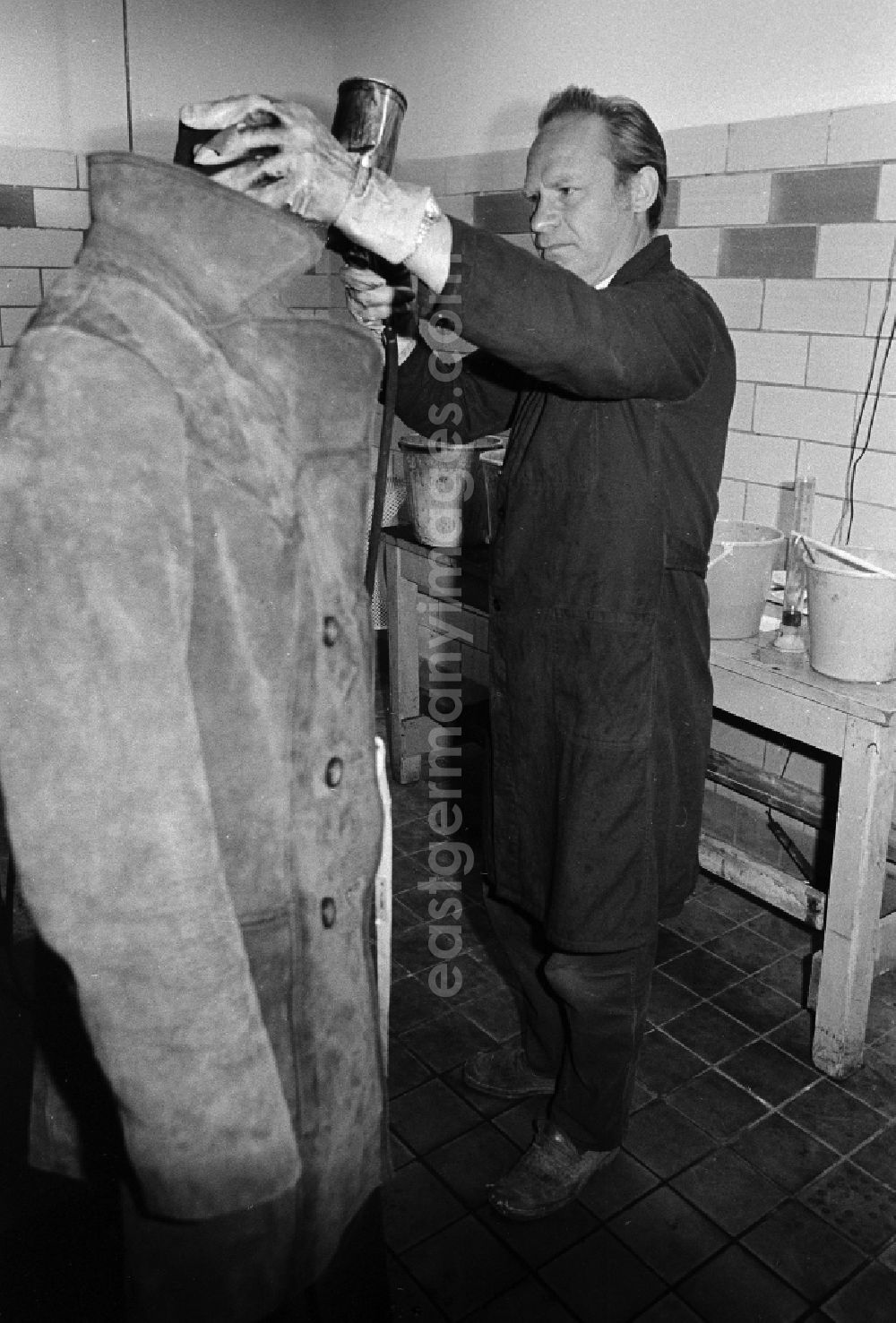 GDR photo archive: Berlin - A worker in the VEB united laundrys Berlin Rewatex with clean of a coat in Berlin, the former capital of the GDR, German democratic republic