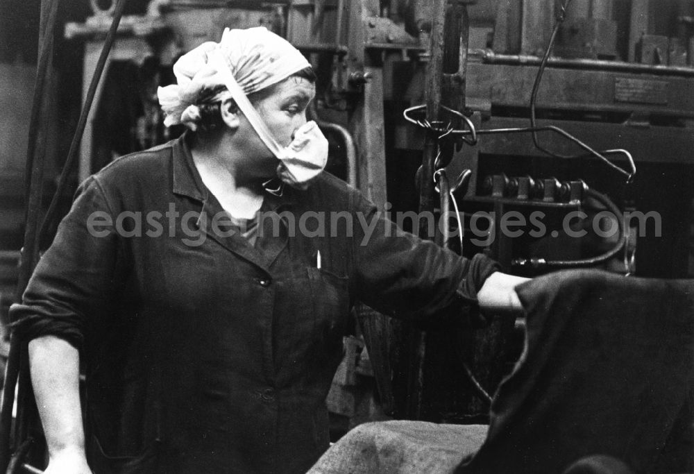 GDR image archive: Lauchhammer - A worker with smock, headscarf and mask in her job in the briquet factory of the brown coal refining VEB in Lauchhammer in the federal state Brandenburg in the area of the former GDR, German democratic republic