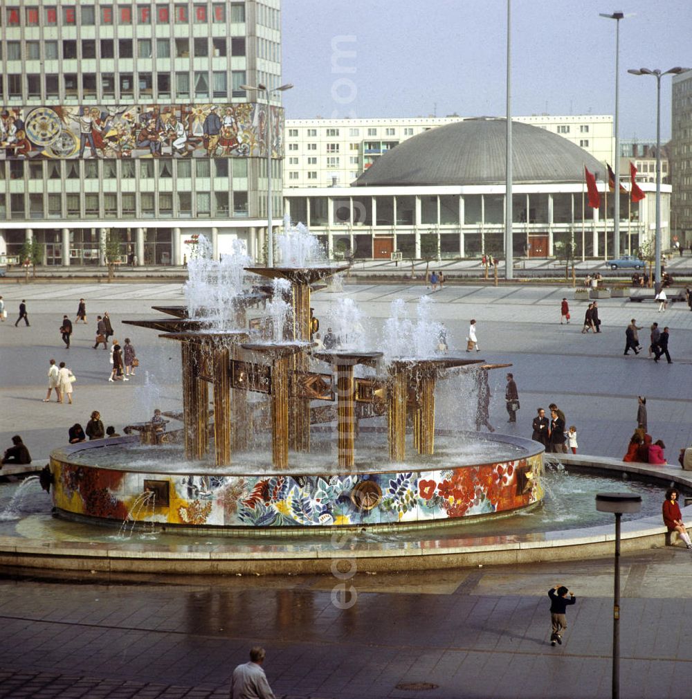 Berlin: Touristen und Einheimische laufen am Brunnen der Völkerfreundschaft über den Berliner Alexanderplatz. Der 197