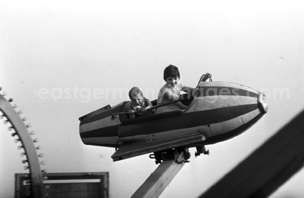 GDR picture archive: Leipzig - Die Leipziger Kleinmesse am Cottaweg im westlichen Stadtteil der Messestadt ist ein beliebtes Volksfest bei Jung und Alt - hier fliegen gerade zwei Kinder in der Rakete eines Fahrgeschäftes in den Himmel hinein.