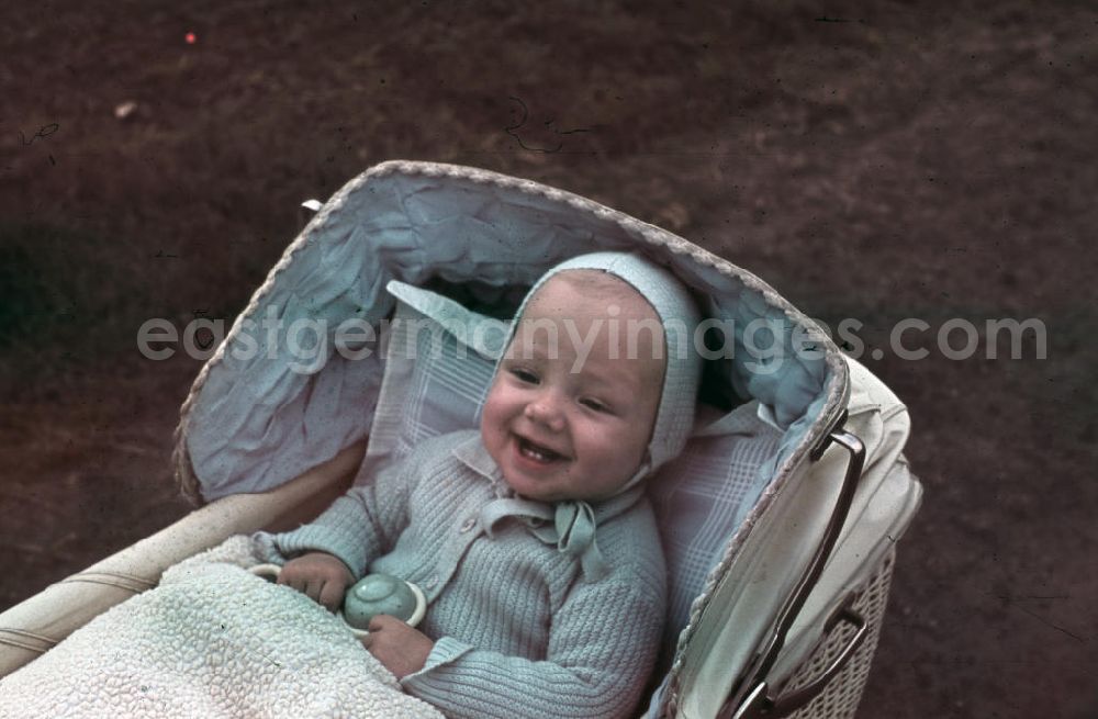 GDR picture archive: Merseberg - Baby sitzt im Kinderwagen und lacht. Baby is sitting in a pram / buggy and laughs.