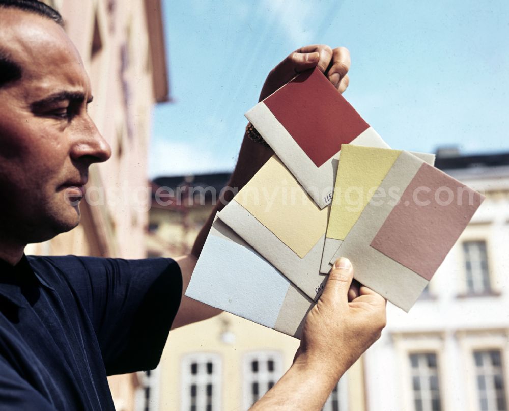 Bad Lobenstein: A man presents color cards for the design of the houses on the market in Bad Lobenstein, Thuringia in the territory of the former GDR, German Democratic Republic