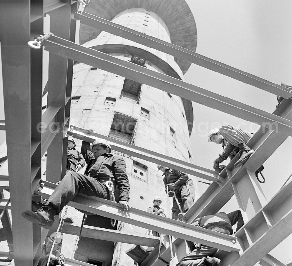 GDR picture archive: Berlin - Construction workers secured with ropes and carabiners during steel girder work on the sliding core of the Berlin TV Tower in the district Mitte in Berlin, the former capital of the GDR, German Democratic Republic