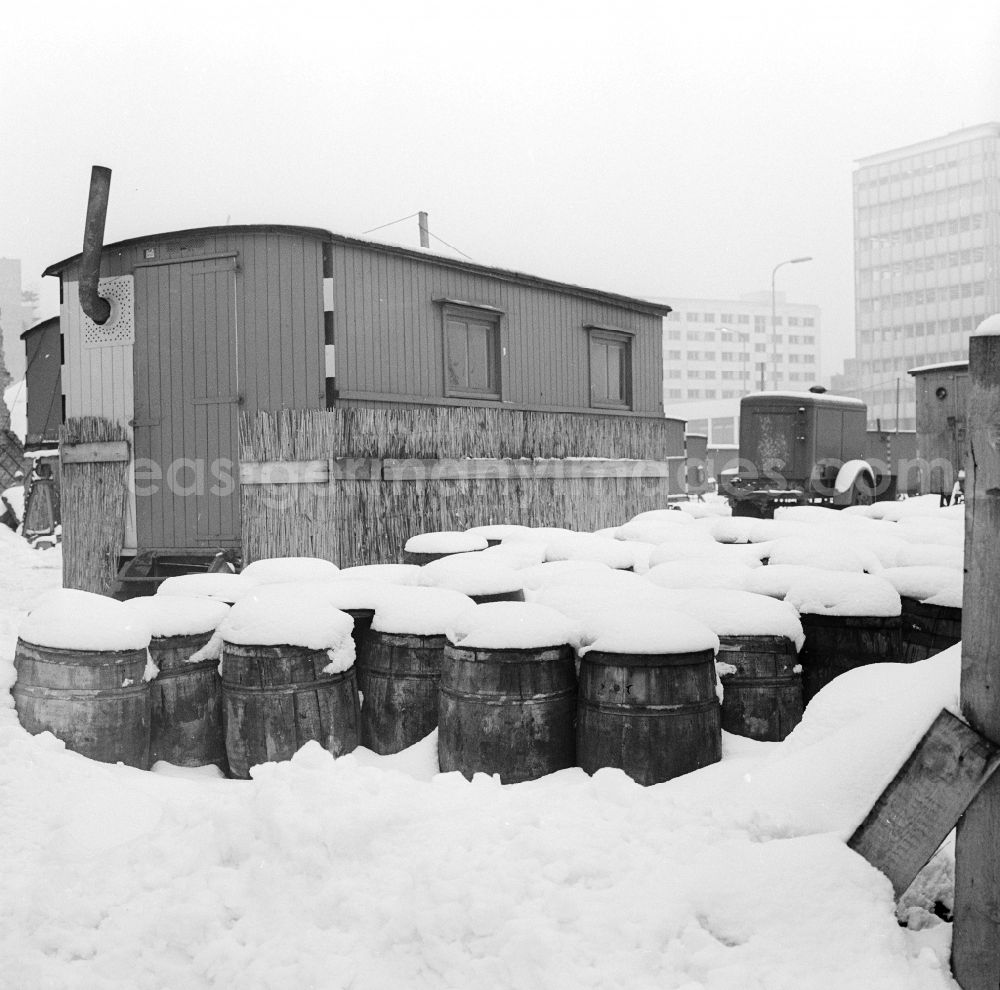 Berlin: A construction wagon with stovepipe and snow-covered barrels on a construction site in Berlin, the former capital of the GDR, German Democratic Republic