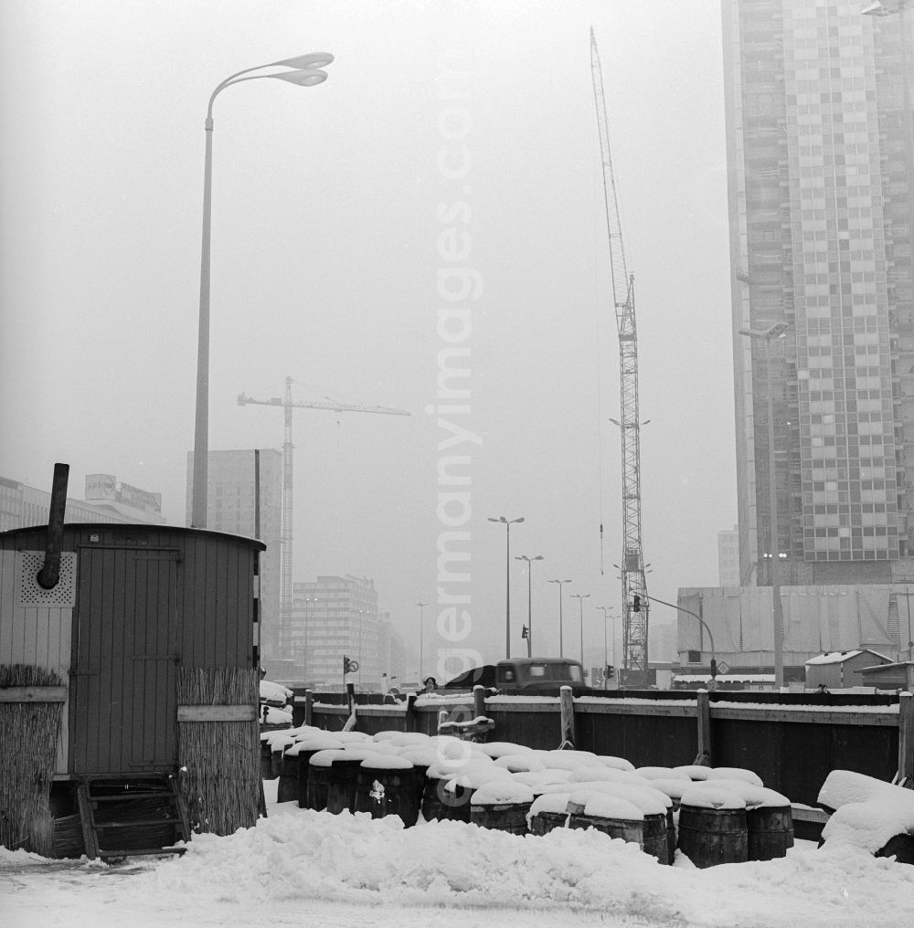 GDR photo archive: Berlin - A construction wagon with stovepipe and snow-covered barrels on a construction site in Berlin, the former capital of the GDR, German Democratic Republic