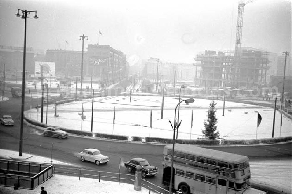 GDR photo archive: Berlin-Mitte - Verschneiter Kreisverkehr auf dem Alexanderplatz. Bus biegt ab, Autos fahren auf Straße. Baustelle Haus des Lehrers mit Kran im Hintergrund.