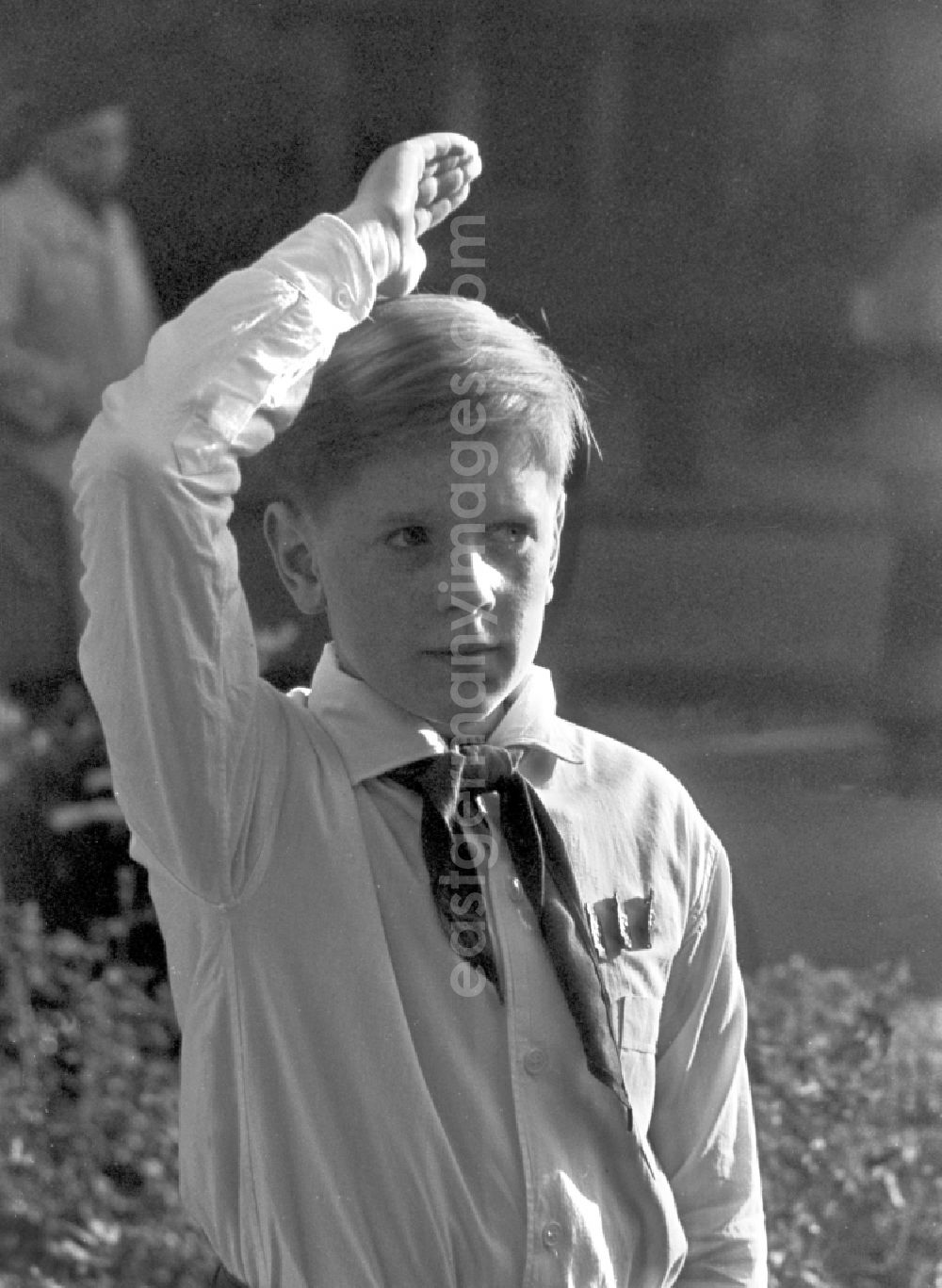 Berlin: A Young Pioneer with white shirt and a pioneer scarf salutes the pioneer Greeting