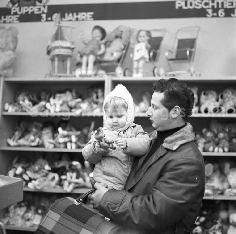 GDR image archive: Berlin - Ein Vater steht mit seiner Tochter auf dem Arm in einem Spielwarengeschäft in der Schönhauser Allee in Berlin. Die Schönhauser Allee gehörte zu den beliebtesten Einkaufsstraßen in Ost-Berlin.