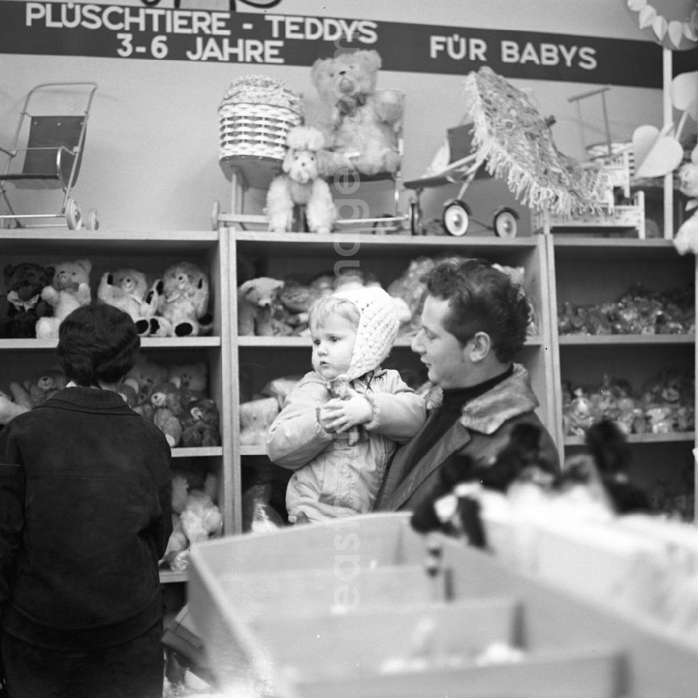 GDR picture archive: Berlin - Ein Vater steht mit seiner Tochter auf dem Arm in einem Spielwarengeschäft in der Schönhauser Allee in Berlin. Die Schönhauser Allee gehörte zu den beliebtesten Einkaufsstraßen in Ost-Berlin.