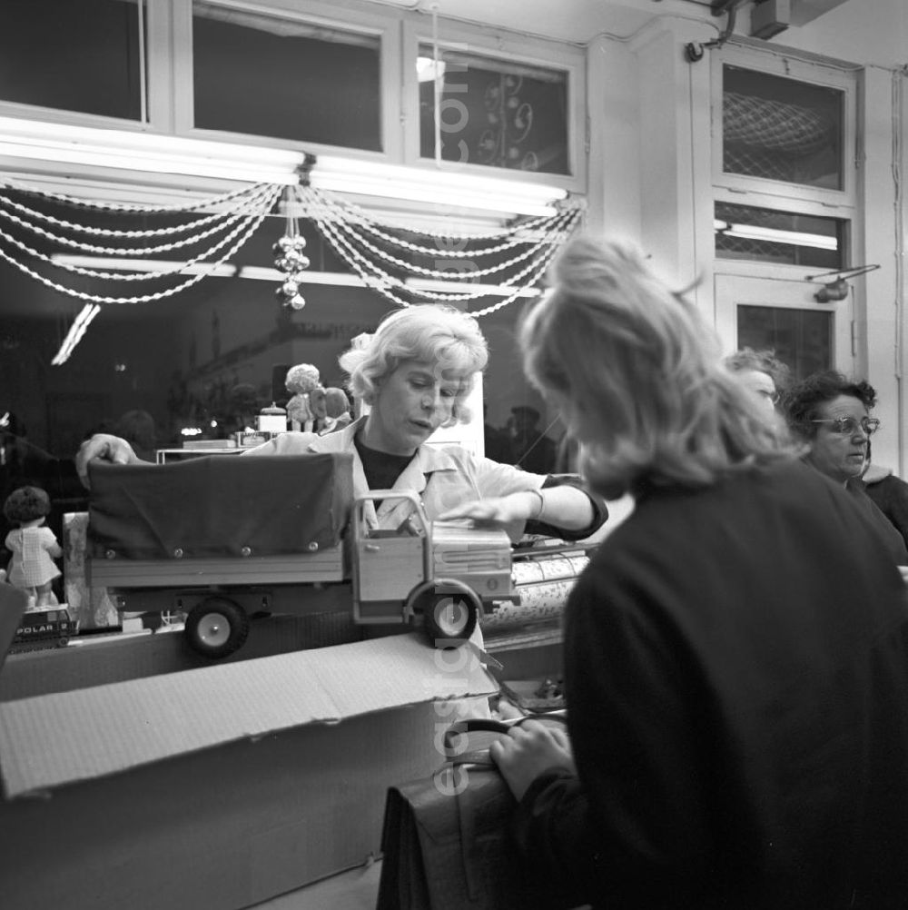 GDR picture archive: Berlin - Einen Monat vor Weihnachten präsentiert eine Verkäuferin einer Kundin in einem Spielwarengeschäft in der Schönhauser Allee in Berlin einen Holz-LKW. Die Schönhauser Allee gehörte zu den beliebtesten Einkaufsstraßen in Ost-Berlin.
