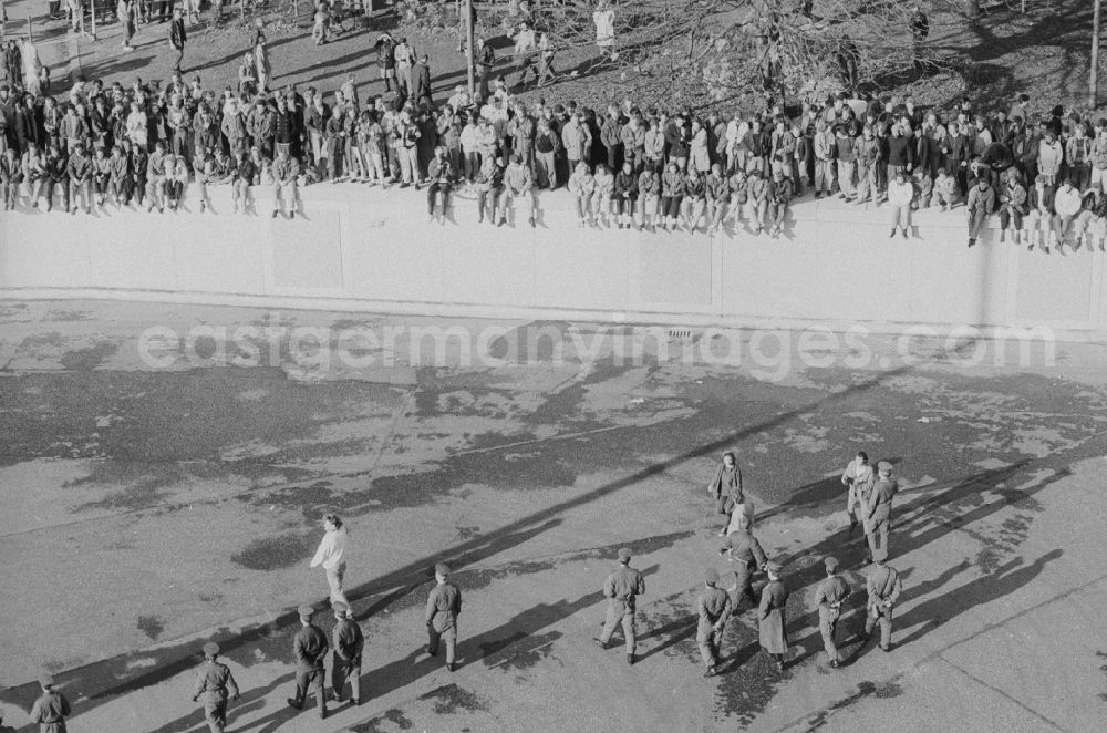 GDR image archive: Berlin - Occupation of the tank wall at the front of the Brandenburg Gate in Berlin-Mitte. Several hundred people from West Berlin climbed and occupied the meter-high concrete barriers of the GDR border on the square in front of the Berlin landmark under the eyes of onlookers soldiers of the Border Troops of the GDR