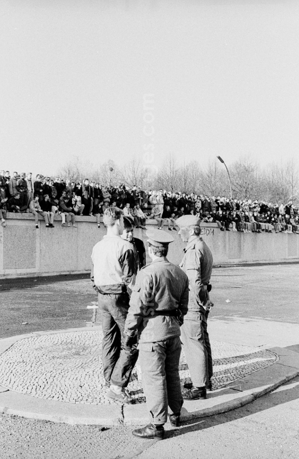 GDR photo archive: Berlin - Occupation of the tank wall at the front of the Brandenburg Gate in Berlin-Mitte. Several hundred people from West Berlin climbed and occupied the meter-high concrete barriers of the GDR border on the square in front of the Berlin landmark under the eyes of onlookers soldiers of the Border Troops of the GDR