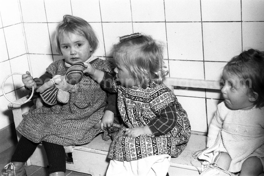 GDR picture archive: Dresden - Fun and games for small children cared for by educators in a kindergarten on a bench in Dresden in the state of Saxony in the area of the former GDR, German Democratic Republic