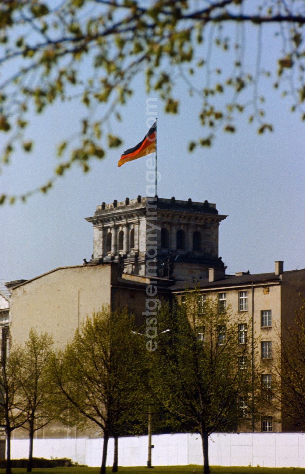 GDR image archive: Berlin - View over the wall towards the Reichstag with tower and Germany flag in Berlin-Mitte on the territory of the former GDR, German Democratic Republic