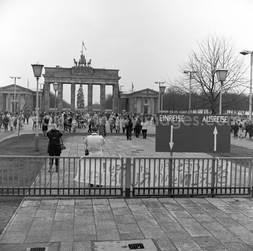 GDR photo archive: Berlin - Tourists and Berlin citizens walk shortly before the fall of the Wall at the Brandenburg Gate in Berlin. In the background is still closed Berlin Wall. In the foreground a sign that read entry / departure