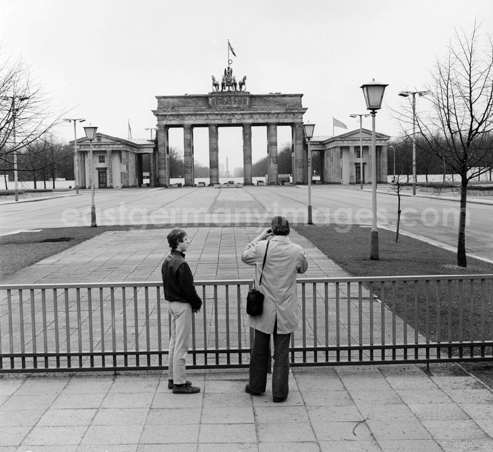 GDR photo archive: Berlin - Tourists to the fortifications at the Brandenburg Gate in Berlin, the former capital of the GDR, the German Democratic Republic. The construction of the Berlin Wall in 1961 - the bulwark of the East - belonged to the Brandenburg Gate to the border-restricted area. It became a symbol of the Cold War