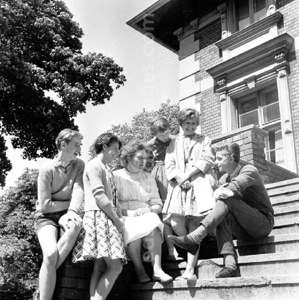 GDR picture archive: Brandenburg - Junge Leute / Jugendliche sitzen auf Treppe vor Gebäude zusammen.