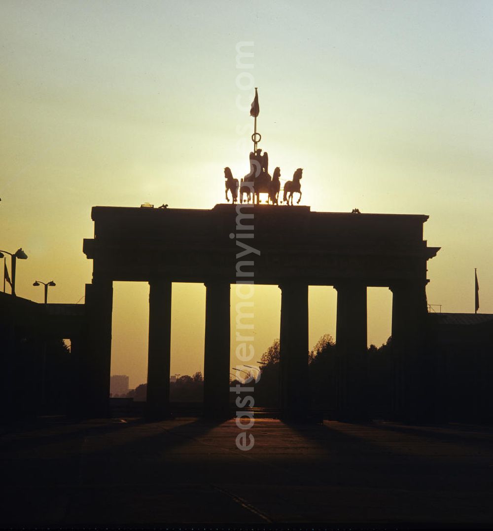 GDR photo archive: Berlin - Bei diesem idyllischen Sonnenuntergang hinter dem Brandenburger Tor erinnert nichts daran, dass Berlin seit über zehn Jahren eine geteilte Stadt ist. Nur bei genauerem Hinschauen lassen sich die Absperrungen am Tor erahnen. Mit dem Bau der Berliner Mauer 1961 gehörte das Brandenburger Tor zum Grenz-Sperrgebiet. Es wurde zum Symbol des Kalten Krieges.