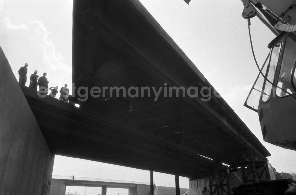GDR picture archive: Berlin - Brückenarbeiten in Marzahn an der Berliner Chaussee. Blick vorbei am Kran auf die fast fertigtgestellte Brücke. Bauarbeiter stehen auf Brücke.