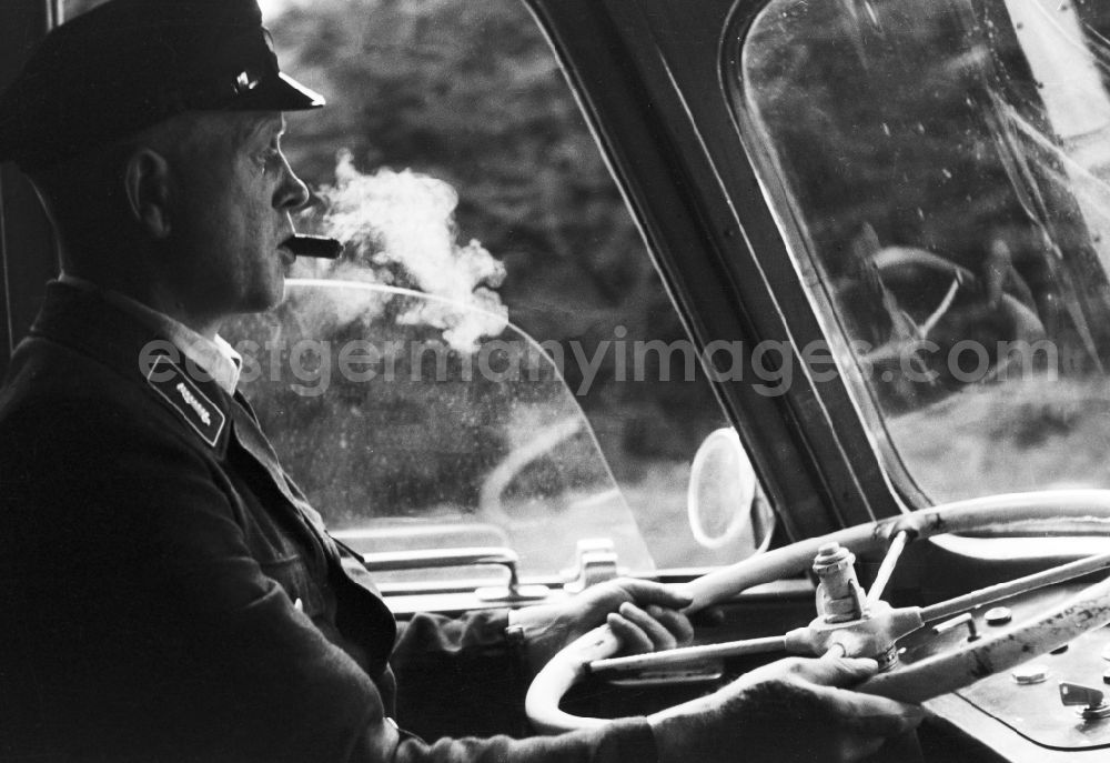 GDR picture archive: Halberstadt - A bus driver with cigar in the mouth in the steering wheel of a coach in Halberstadt in the federal state Saxony-Anhalt in the area of the former GDR, German democratic republic