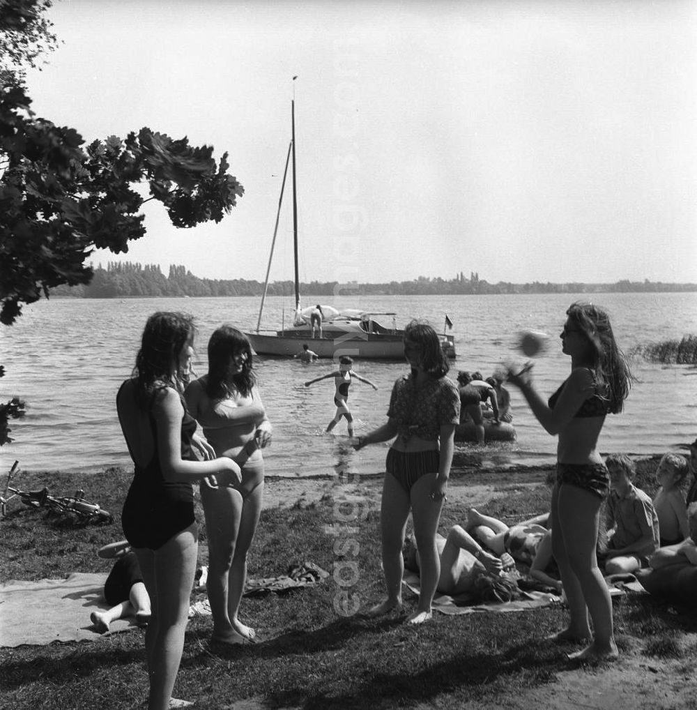 GDR photo archive: Berlin Köpenick - Campingurlaub am Krossinsee. Urlauber beim Baden und Sonnen. Eine Gruppe junger Frauen spielt Ball. Im Hintergrund ein Schlauchboot und ein Segelschiff.