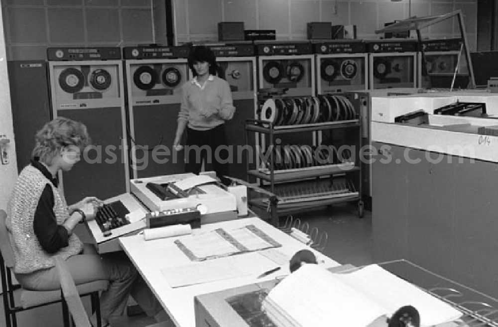 GDR picture archive: Erfurt - Zwei junge Frauen in einem Datenverarbeitungsbetrieb VEB Robotron-Optima Erfurt. Eine Frau sitzt an Schreibgerät / Schreibmaschine und eine stehet an Abspieleräten für Magnetbänder.