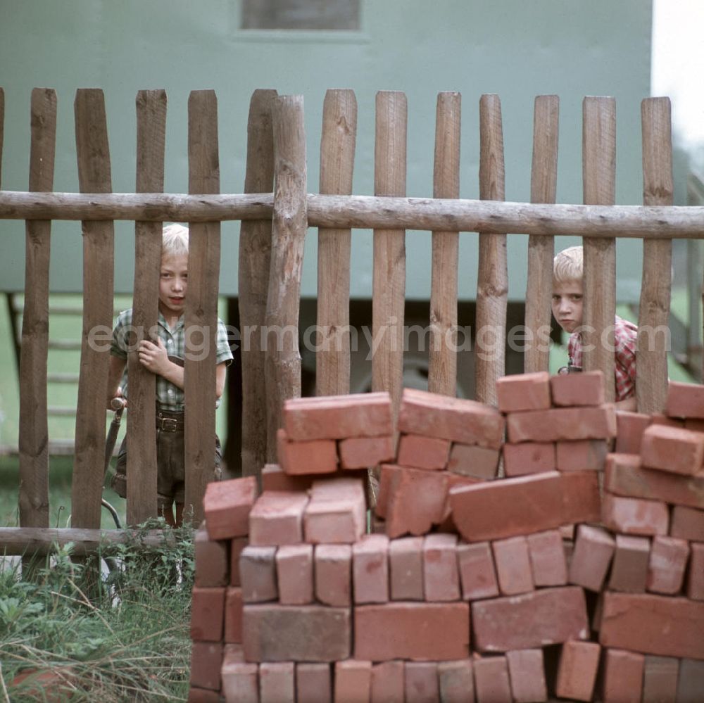 GDR picture archive: Leipzig - Kinder beobachten durch einen Zaun den Bau einer Volksschwimmhalle in Leipzig. Volksschwimmhallen wurden in den 1960er und 197