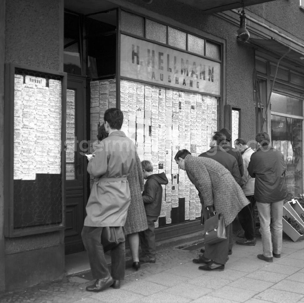 GDR photo archive: Berlin - Passanten stehen vor einem Geschäft in der Schönhauser Allee in Berlin-Prenzlauer Berg und studieren die ausgehängten Anzeigen auf der Suche nach einem Schnäppchen. Die Schönhauser Allee gehörte zu den beliebtesten Einkaufsstraßen im Berliner Osten.