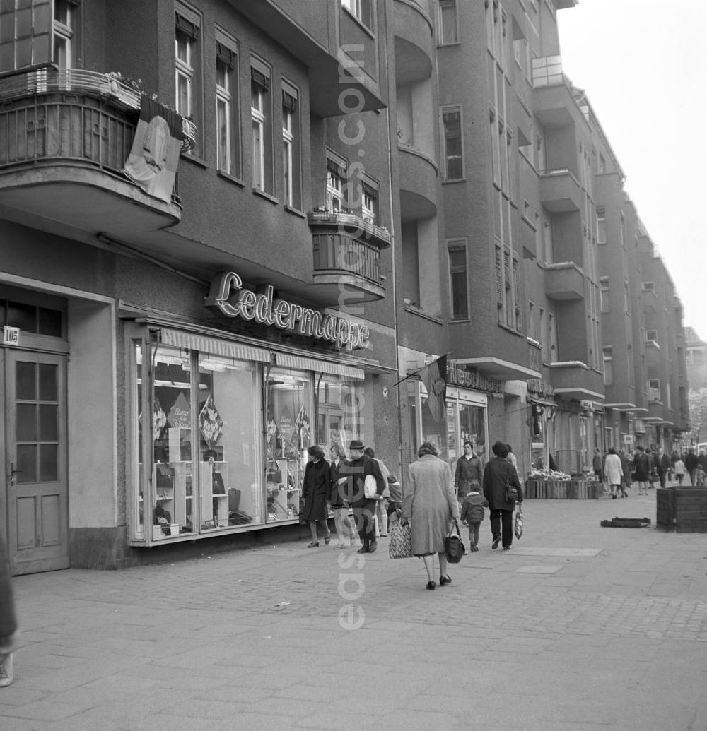 GDR photo archive: Berlin - Straßenszene in der Schönhauser Allee in Berlin-Prenzlauer Berg - vereinzelt hängen noch DDR-Fahnen vom 1. Mai an den Balkons und Geschäften. Die Schönhauser Allee gehörte mit ihren vielen Geschäften zu den beliebtesten Einkaufsstraßen des Berliner Osten.