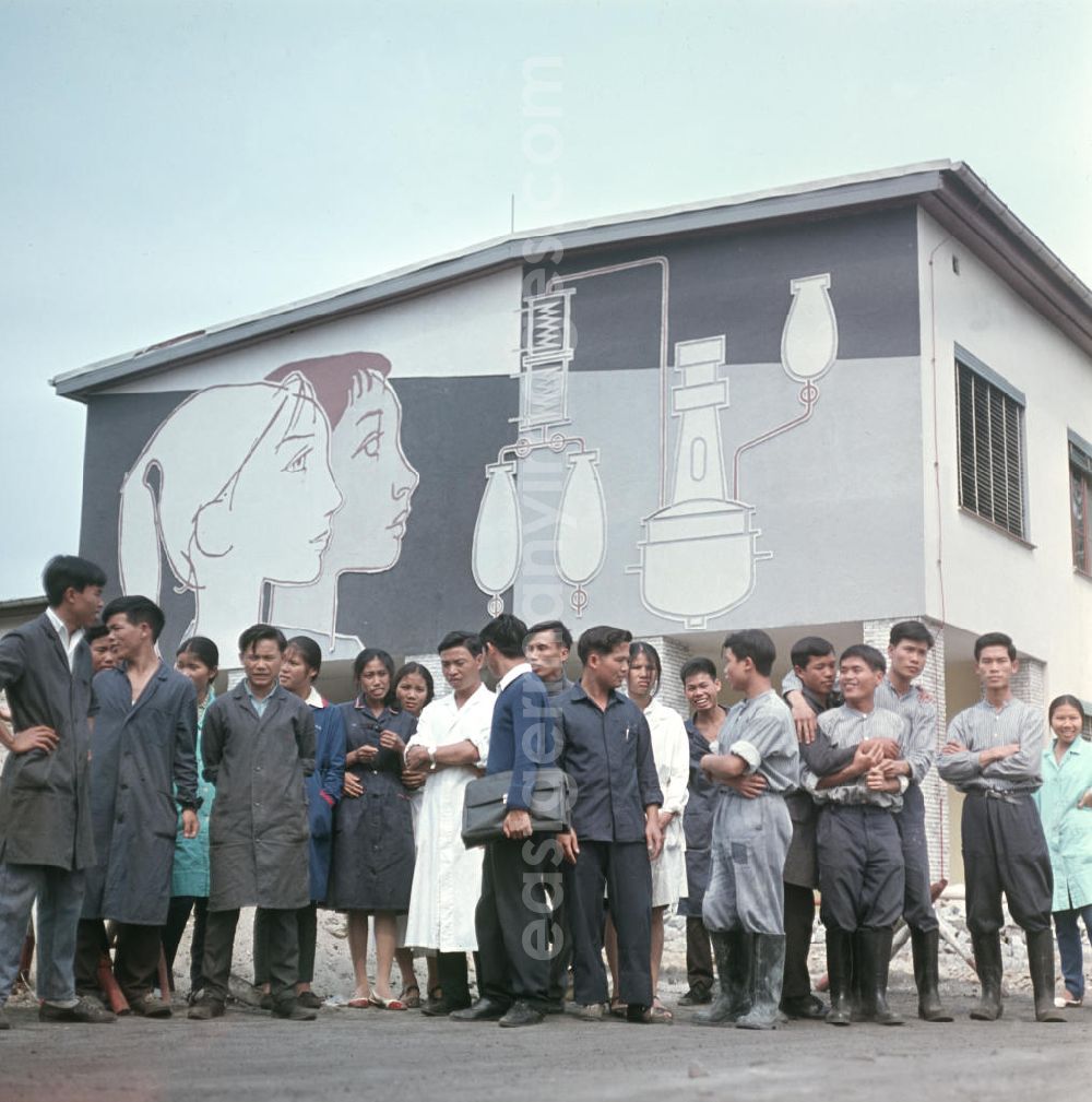 GDR image archive: Berlin - Vietnamesische Praktikanten stehen vor den Gebäuden des VEB Berlin-Chemie, wo sie ihre Ausbildung absolvieren. Vietnamesen bildeten in der DDR die größte Gruppe an Arbeitskräfte aus den sozialistischen Bruderländern.