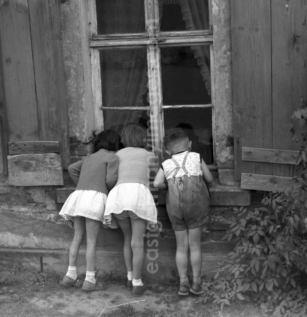 GDR image archive: Pomßen - Guck mal, da - Kinder spielen auf einer Straße in dem kleinen Dorf Pomßen in der Nähe von Leipzig und schauen neugierig in das Fenster eines alten Hauses.