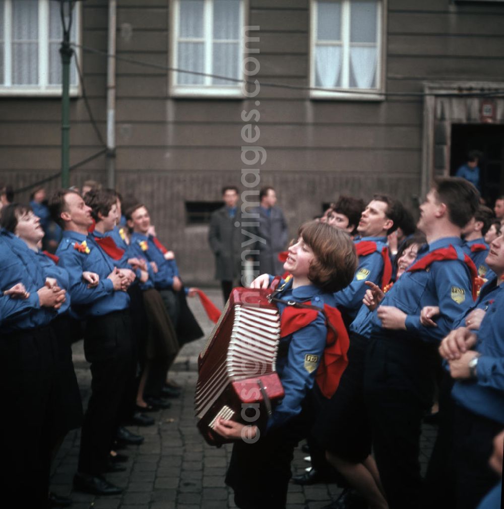 GDR image archive: Berlin - Auf einer Jugenddemonstration singen und tanzen FDJler in Uniform zur Musik eines Akkordeons in Berlin.